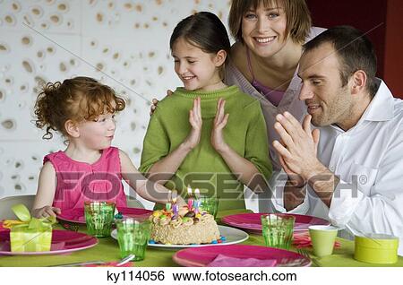 Couple and 2 little girls with birthday cake at lunch table View Large Photo Image Stock Photograph - Couple and 2 little girls with birthday cake at lunch table. Fotosearch