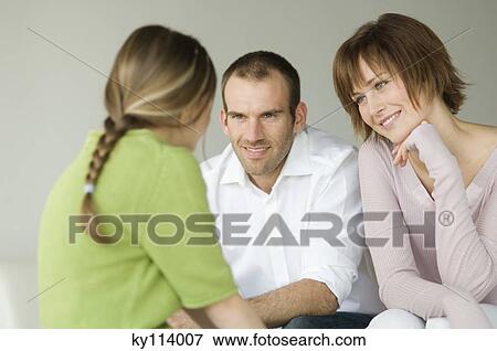 Couple and little girl talking, sitting in living-room View Large Photo Image Stock Photo - Couple and little girl talking, sitting in living-room. Fotosearch