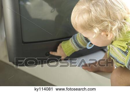 Stock Image - Little boy turning on TV. Fotosearch