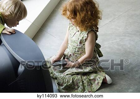 Little girl kneeling in front of television, holding remote control, elevated view View Large Photo Image Stock Image - Little girl kneeling in front of television, holding remote control, elevated view. Fotosearch