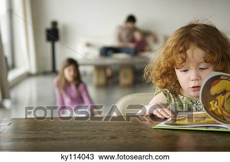 Little girl reading children's book, family in the background View Large Photo Image Stock Image - Little girl reading children's book, family in the background. Fotosearch