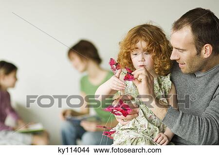 Man and little girl playing with butterfly garland, woman and child in the background View Large Photo Image Picture - Man and little girl playing with butterfly garland, woman and child in the background. Fotosearch