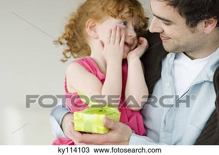 Stock Image - Man giving present to little girl. Fotosearch