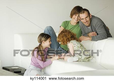 Smiling couple and 2 little girls in the living-room View Large Photo Image Stock Image - Smiling couple and 2 little girls in the living-room. Fotosearch