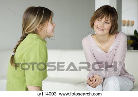 Smiling woman and little girl sitting in living-room View Large Photo Image Stock Image - Smiling woman and little girl sitting in living-room. Fotosearch