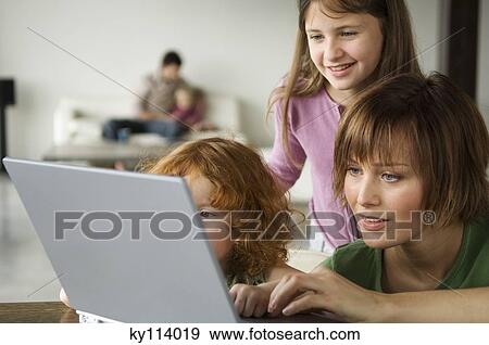 Woman and 2 little girls using laptop computer, man and child in the background View Large Photo Image Stock Photo - Woman and 2 little girls using laptop computer, man and child in the background. Fotosearch