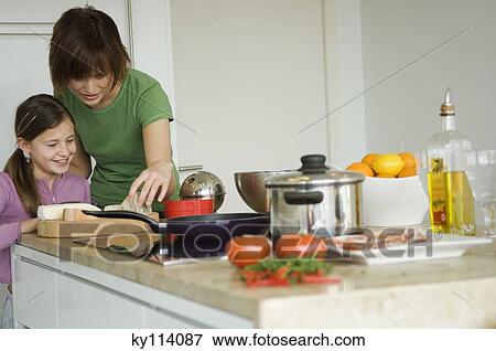 Stock Photo - Woman and little girl in the kitchen, preparing cheese tray. Fotosearch