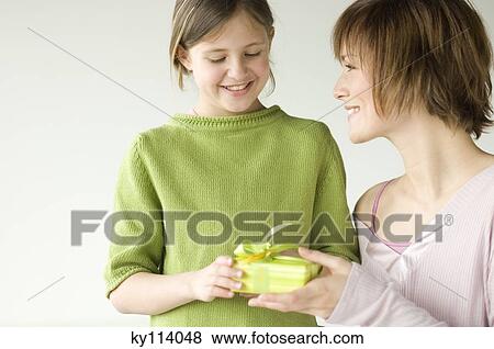 Woman giving a present to little girl View Large Photo Image Stock Photo - Woman giving a present to little girl. Fotosearch