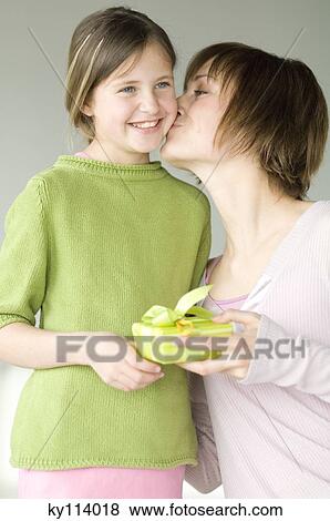 Woman holding present, kissing little girl on her cheek View Large Photo Image Stock Photo - Woman holding present, kissing little girl on her cheek. Fotosearch