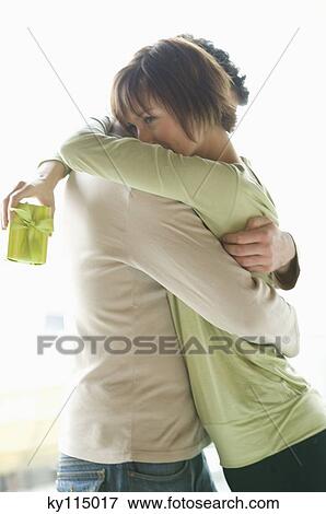 Couple embracing, woman holding present View Large Photo Image Stock Photo - Couple embracing, woman holding present. Fotosearch