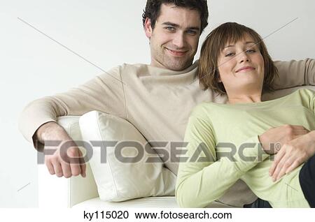 Couple lying on a sofa, smiling for the camera View Large Photo Image Stock Image - Couple lying on a sofa, smiling for the camera. Fotosearch