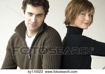 Couple sitting back to back, looking at the camera View Large Photo Image Stock Image - Couple sitting back to back, looking at the camera. Fotosearch