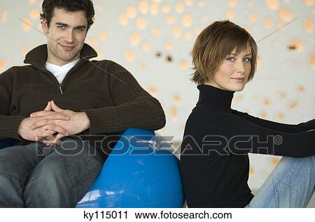 Couple sitting in living-room, looking at the camera View Large Photo Image Stock Image - Couple sitting in living-room, looking at the camera. Fotosearch