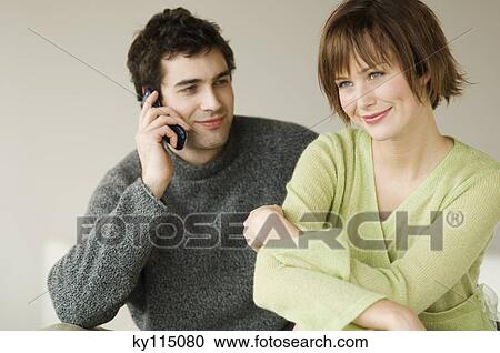 Couple sitting in living-room, man using a mobile phone View Large Photo Image Stock Image - Couple sitting in living-room, man using a mobile phone. Fotosearch