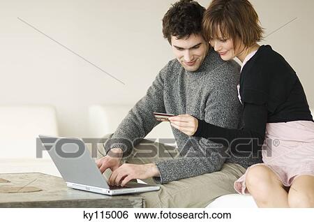 Man using laptop computer, woman holding credit card View Large Photo Image Stock Photograph - Man using laptop computer, woman holding credit card. Fotosearch