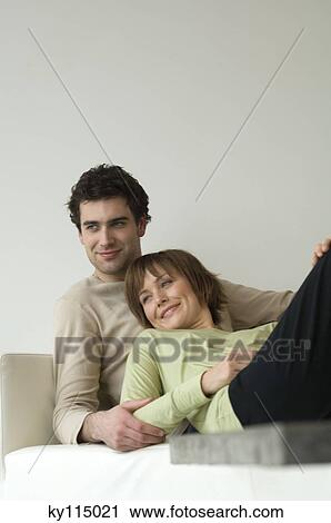 Stock Image - Smiling couple lying on a sofa. Fotosearch