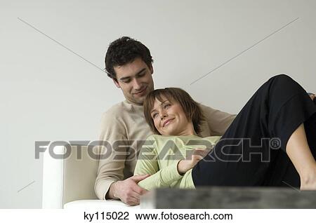 Stock Image - Smiling couple lying on a sofa. Fotosearch