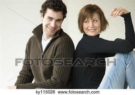 Smiling couple sitting back to back View Large Photo Image Stock Photograph - Smiling couple sitting back to back. Fotosearch
