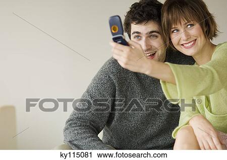Stock Image - Smiling couple taking picture with camera phone. Fotosearch