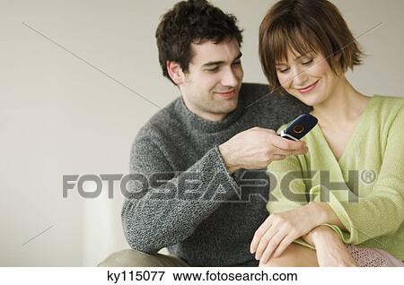 Smiling couple using mobile phone View Large Photo Image Stock Photo - Smiling couple using mobile phone. Fotosearch
