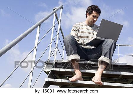 人間が座る 上に 階段 ラップトップを使用して 屋外で 低い 角度 ストックイメージ Ky Fotosearch