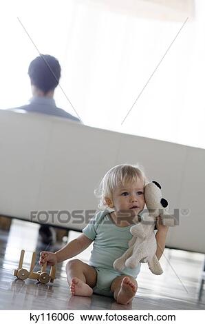 Little boy with stuffed dog sitting on the floor, man in the background View Large Photo Image Stock Photograph - Little boy with stuffed dog sitting on the floor, man in the background. Fotosearch
