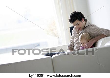 Man and little boy sitting on a sofa in a living-room View Large Photo Image Stock Image - Man and little boy sitting on a sofa in a living-room. Fotosearch