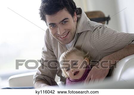 Man and little boy sitting on a sofa, smiling for the camera View Large Photo Image Stock Image - Man and little boy sitting on a sofa, smiling for the camera. Fotosearch