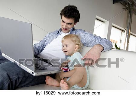 Stock Photo - Man and little boy using laptop computer. Fotosearch