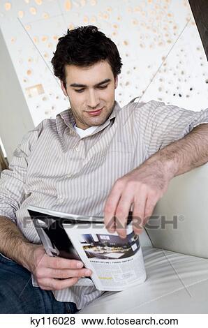 Man sitting on a sofa, reading a magazine View Large Photo Image Stock Photo - Man sitting on a sofa, reading a magazine. Fotosearch