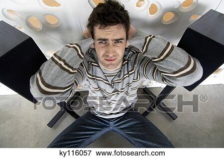 Man sitting on the floor between 2 speakers, with hands over ears, elevated view View Large Photo Image Stock Photo - Man sitting on the floor between 2 speakers, with hands over ears, elevated view. Fotosearch