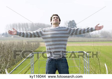 Man standing on a terrace, arms outstretched View Large Photo Image Picture - Man standing on a terrace, arms outstretched. Fotosearch