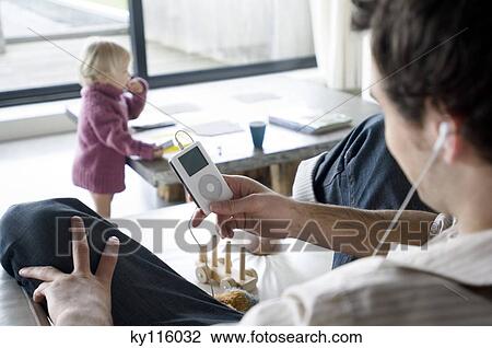 Man using iPod in a living-room, little boy in the background View Large Photo Image Stock Image - Man using iPod in a living-room, little boy in the background. Fotosearch