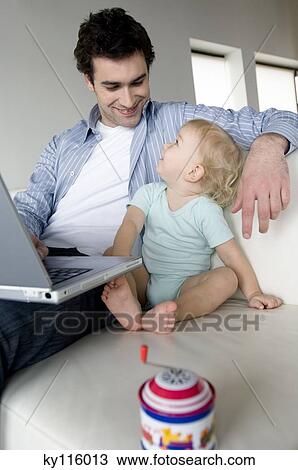 Man using laptop computer and little boy looking at each other, sitting on a sofa View Large Photo Image Stock Image - Man using laptop computer and little boy looking at each other, sitting on a sofa. Fotosearch