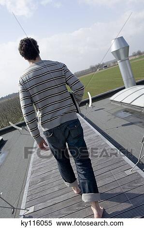 Man walking on terrace roof, holding laptop computer, rear view View Large Photo Image Stock Photography - Man walking on terrace roof, holding laptop computer, rear view. Fotosearch