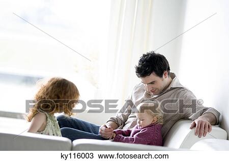 Man with 2 children sitting in a living-room View Large Photo Image Stock Image - Man with 2 children sitting in a living-room. Fotosearch