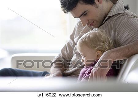 Man with little boy sitting on a sofa, side view View Large Photo Image Stock Image - Man with little boy sitting on a sofa, side view. Fotosearch