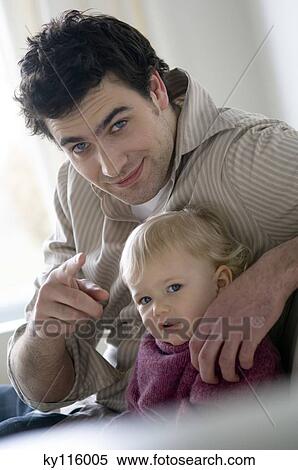 Man with little boy sitting on a sofa, looking at the camera View Large Photo Image Stock Photography - Man with little boy sitting on a sofa, looking at the camera. Fotosearch