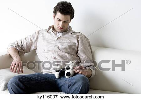 Sad looking man sitting on a sofa, holding stuffed dog View Large Photo Image Stock Photo - Sad looking man sitting on a sofa, holding stuffed dog. Fotosearch