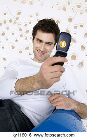 Smiling man taking picture with camera phone View Large Photo Image Stock Photograph - Smiling man taking picture with camera phone. Fotosearch