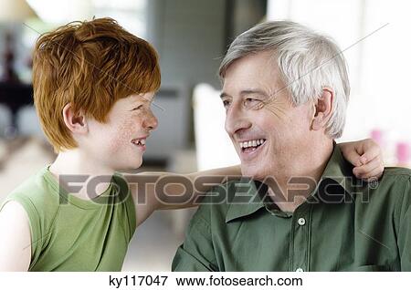 Stock Photo - Boy embracing senior man, looking at each other. Fotosearch