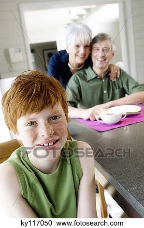 Stock Image - Boy looking at the camera, senior couple embracing in background. Fotosearch