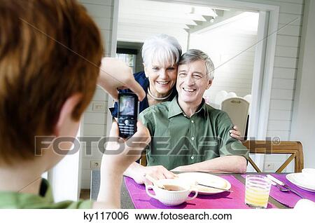 Boy taking picture of senior couple with camera phone View Large Photo Image Stock Photograph - Boy taking picture of senior couple with camera phone. Fotosearch