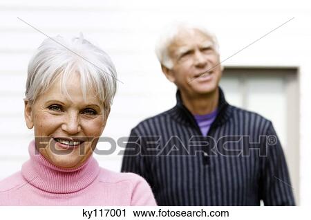 Portrait of a senior woman smiling for the camera, senior man in background View Large Photo Image Stock Image - Portrait of a senior woman smiling for the camera, senior man in background. Fotosearch