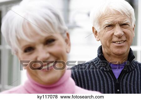 Stock Photo - Portrait of a senior woman smiling for the camera, senior man in background. Fotosearch