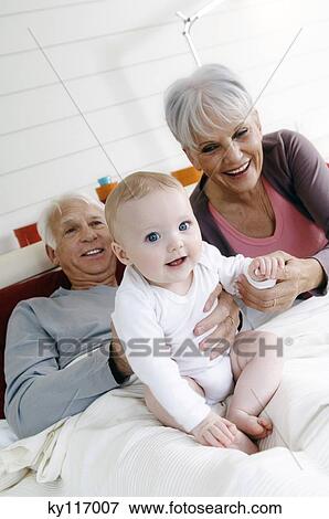 Stock Photo - Senior couple and baby girl in bed. Fotosearch