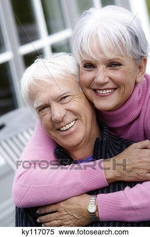 Senior couple embracing, smiling for the camera, outdoors View Large Photo Image Stock Photography - Senior couple embracing, smiling for the camera, outdoors. Fotosearch