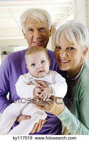 Senior couple holding a baby girl, looking at the camera View Large Photo Image Stock Photo - Senior couple holding a baby girl, looking at the camera. Fotosearch