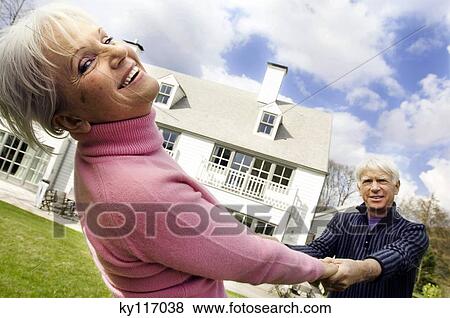 Senior couple holding hands outdoors, house in background View Large Photo Image Stock Photo - Senior couple holding hands outdoors, house in background. Fotosearch