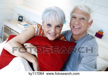 Senior couple sitting on a bed, smiling for the camera View Large Photo Image Picture - Senior couple sitting on a bed, smiling for the camera. Fotosearch